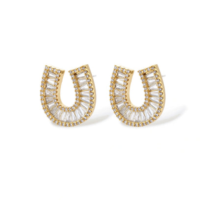 Gold-plated horseshoe necklace and earring set with baguette and round crystals arranged in geometric pattern on white background.