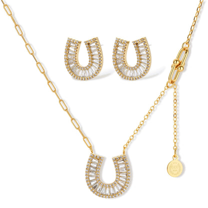Gold-plated horseshoe necklace and earring set with baguette and round crystals arranged in geometric pattern on white background.