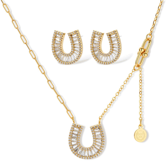 Gold-plated horseshoe necklace and earring set with baguette and round crystals arranged in geometric pattern on white background.